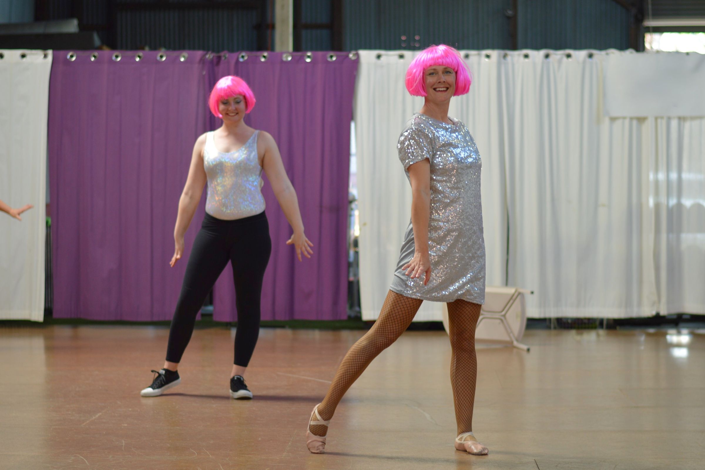 Instructor and student dancing in silver sparkley dance costumes and pink wigs